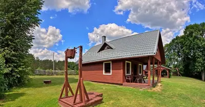 a small red house on a grass field at Dzūkijos uoga in Viršurodukis