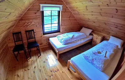 an attic room with two beds and a window at Dzūkijos uoga in Viršurodukis