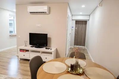 a living room with a table and a flat screen tv at Šviesus ir jaukus butas Šiaulių centre puiki vieta poilsiui in Šiauliai