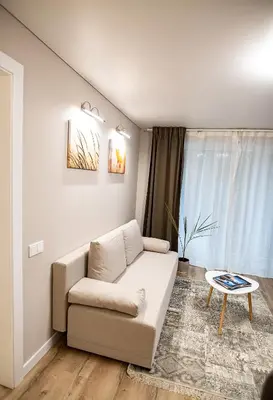 a living room with a couch and a table at Šviesus ir jaukus butas Šiaulių centre puiki vieta poilsiui in Šiauliai