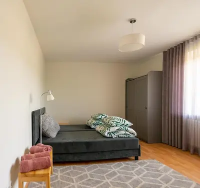 a bedroom with a bed and a chair in it at Apartamentai Tytuvėnuose in Tytuvėnai