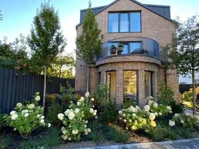 a brick house with flowers in the front yard at Salt Garden Superior double rooms in Druskininkai