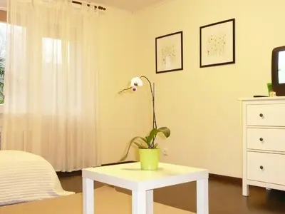 a white table with a plant on it in a bedroom at Apartment Stay In in Druskininkai
