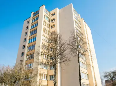 a tall building with a tree in front of it at Apartment Stay In in Druskininkai