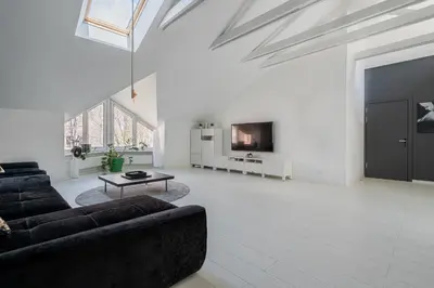a white living room with a couch and a tv at Grey House in Vilnius