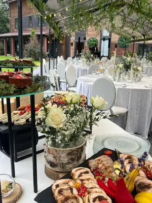 a table topped with plates of food and flowers at Vila Forest Resort in Kvietkučiai