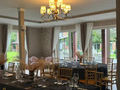 a dining room with a table and chairs and a chandelier at Vila Forest Resort in Kvietkučiai