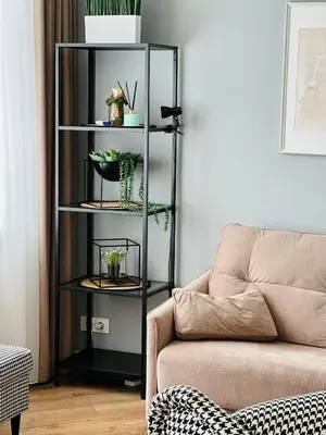 a black book shelf with plants on it next to a couch at Butas pačiame Šiaulių miesto centre in Šiauliai