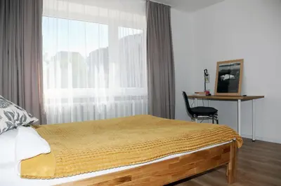 a bedroom with a bed and a window and a chair at Naujai suremontuotas butas miesto centre. in Visaginas