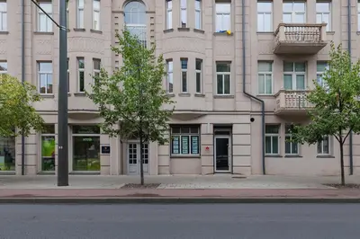 a large building with a tree in front of it at Freedom avenue apartment by Polo Apartments in Kaunas