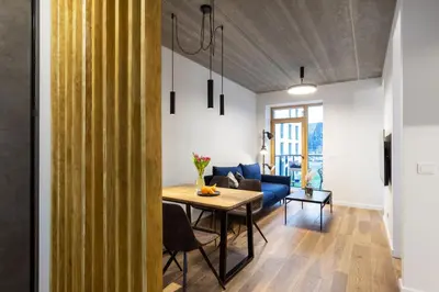 a living room with a table and a blue couch at City Center Sanctuary Modern Business-Class Studio with Free Parking in the Heart of Vilnius in Vilnius