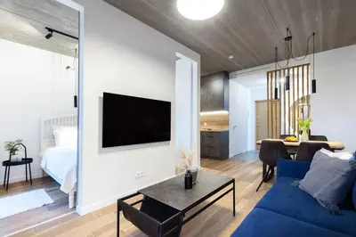 a living room with a blue couch and a tv at City Center Sanctuary Modern Business-Class Studio with Free Parking in the Heart of Vilnius in Vilnius