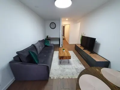 a living room with a black couch and a table at Talsa 1-bedroom apartment in city center Šiauliai in Šiauliai