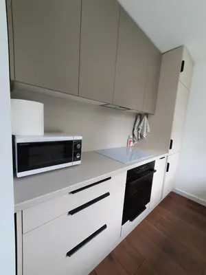 a kitchen with white cabinets and a microwave at Talsa 1-bedroom apartment in city center Šiauliai in Šiauliai