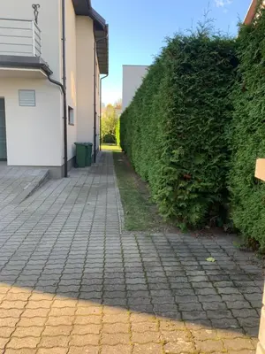 a brick sidewalk next to a hedge next to a building at Kepezinski ECO Apartments in Kaunas
