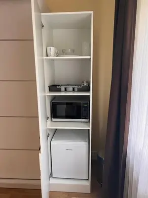 a white book shelf with a microwave on it at Kepezinski ECO Apartments in Kaunas