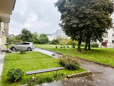 a park with a bench and a tree and a car at Apartamentai Vytauto Street III in Šiauliai