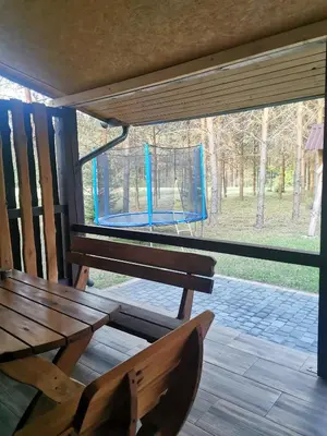 a wooden bench sitting on a porch with a swing at Apartamentai Pušyne in Druskininkai