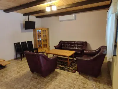 a living room with leather furniture and a table and chairs at Apartamentai Pušyne in Druskininkai