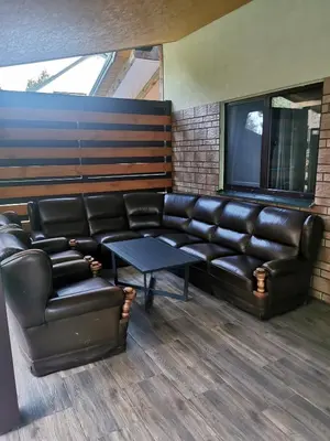 a waiting room with a leather couch and a table at Apartamentai Pušyne in Druskininkai