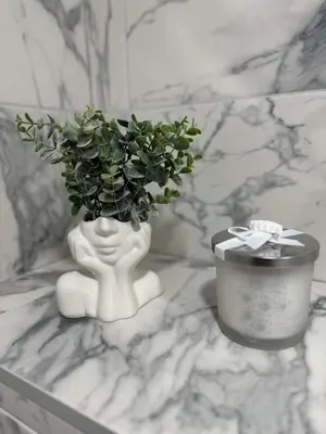 a white vase with a plant and a candle on a counter at VILA ROŽĖ Nakvynė in Raseiniai
