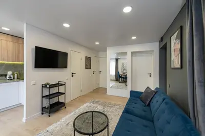 a living room with a blue couch and a kitchen at RIVERFRONT 2BD Old Town Apartment by Domvia in Kaunas