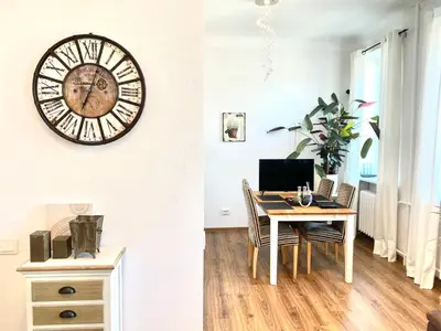 a dining room with a table and a clock on the wall at City Central apartament in Šiauliai