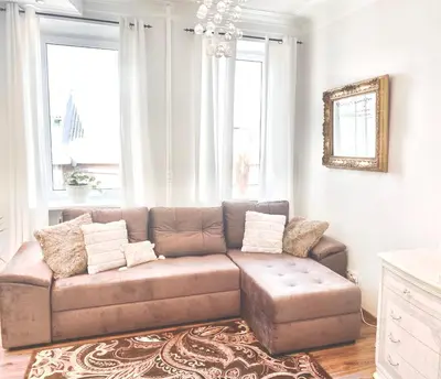 a living room with a brown couch and a chandelier at City Central apartament in Šiauliai