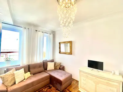 a living room with a couch and a chandelier at City Central apartament in Šiauliai