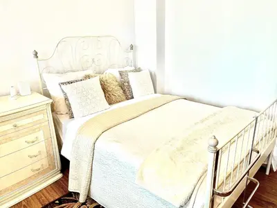 a bedroom with a white bed and a wooden dresser at City Central apartament in Šiauliai