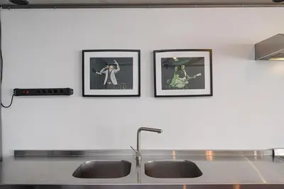 three framed pictures on a wall above a kitchen sink at Hidden Submarine in Vilnius