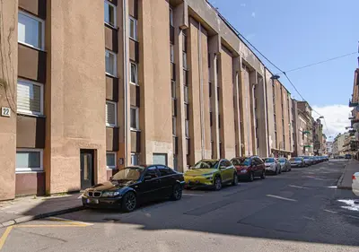 a row of cars parked on a street next to a building at Hidden Submarine in Vilnius