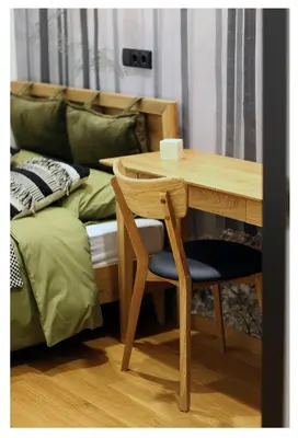 a wooden table and chair next to a bed at Poilsio namelis in Skynimai