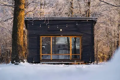 a small log cabin in the woods with a window at Beautiful Tiny house on the lake side. in Trakai