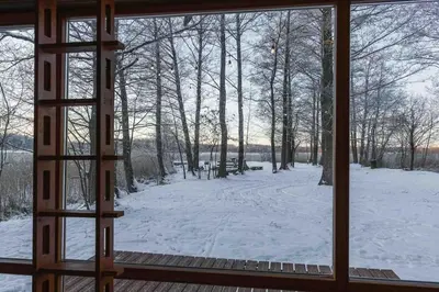 a window looking out at a snow covered yard at Beautiful Tiny house on the lake side. in Trakai