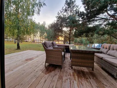 a wooden deck with a couch and a table at Pirties Spa namas in Molėtai
