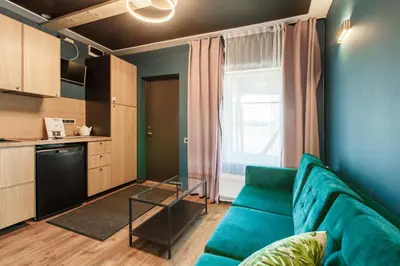 a living room with a blue couch and a kitchen at Apartments in Kaunas in Kaunas