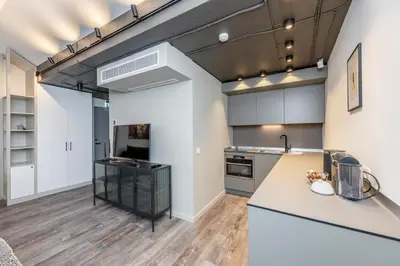 an open kitchen with white cabinets and wood floors at Artsy Exclusive Old Town Residence Gallery Walk in Vilnius