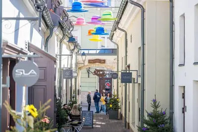 people walking down an alley in a city with colorful lights at Artsy Exclusive Old Town Residence Gallery Walk in Vilnius