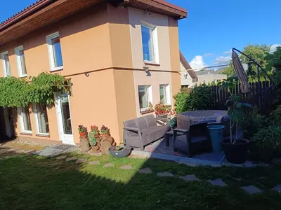 a house with a chair and a table in the yard at Namelis uždarame kieme in Šiauliai