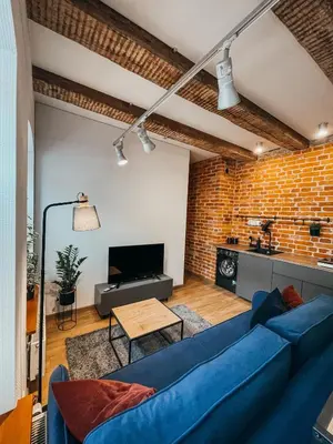 a living room with a blue couch and a brick wall at 1880 Apartment with Private Parking in Marijampolė