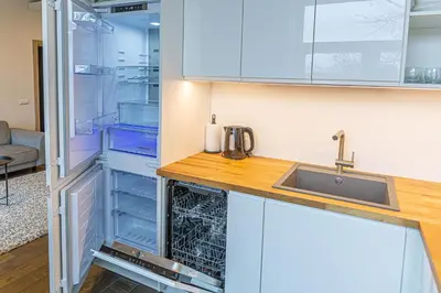 a kitchen with a sink and an empty refrigerator at Žalgiris arena apartment with AC in Kaunas