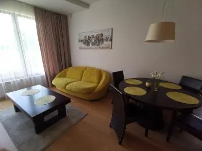 a living room with a table and a yellow chair at Vita Apartment in Druskininkai