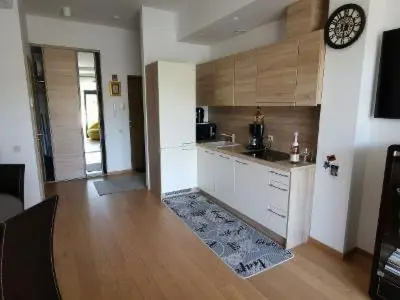 a kitchen with a counter and a clock on the wall at Vita Apartment in Druskininkai