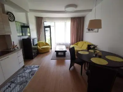 a kitchen and living room with a table and a dining room at Vita Apartment in Druskininkai