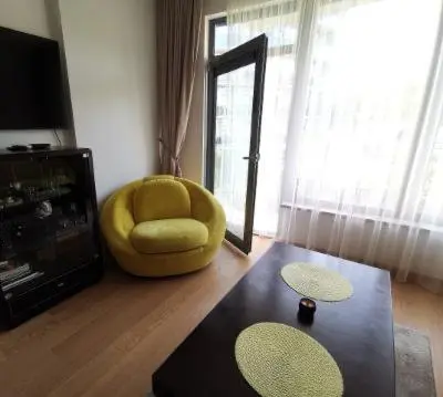a living room with a yellow chair and a mirror at Vita Apartment in Druskininkai