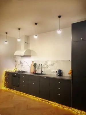 a kitchen with black cabinets and lights in it at NEW! WARM and COSY apartment with private ENTRANCE and PARKING in a city center in Vilnius