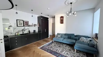 a living room with a blue couch and a kitchen at NEW! WARM and COSY apartment with private ENTRANCE and PARKING in a city center in Vilnius