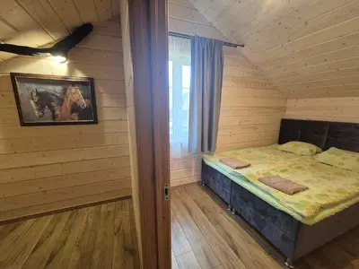 a small room with a bed in a wooden house at Bona Natura Pirtelė in GratiÅ¡kÄ—s
