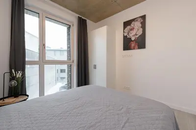 a white bedroom with a bed and a window at Bossa Nova - modern 2 bedroom apartment in the center in Vilnius